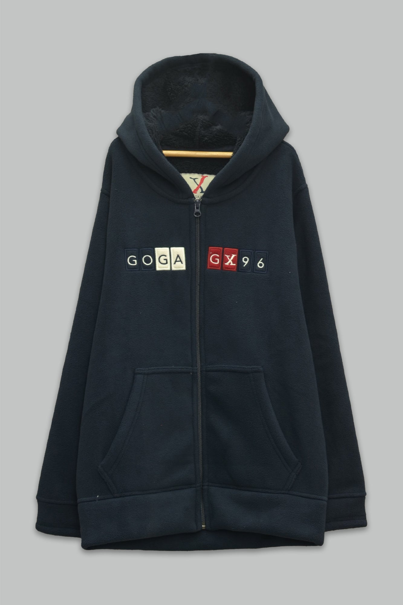 Sudadera sherpa niño bordada con manga larga, capucha ajustable, bolsas frontales y cierre.