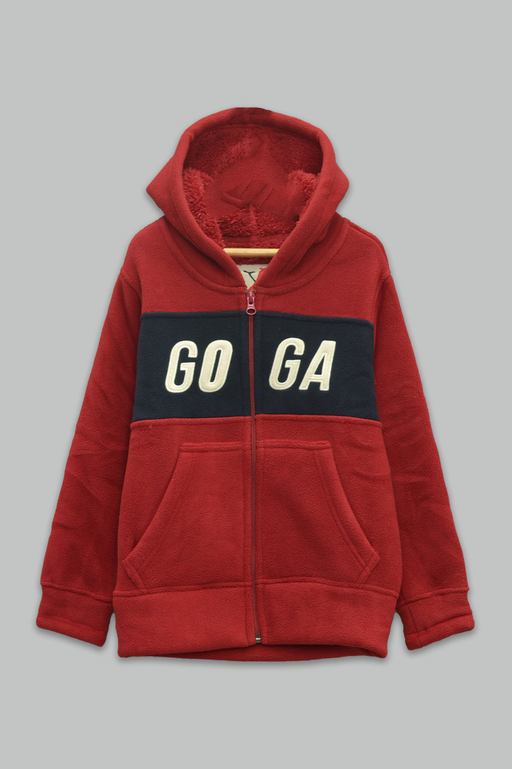 Sudadera sherpa niño bordada con manga larga, capucha ajustable, bolsas frontales y cierre.