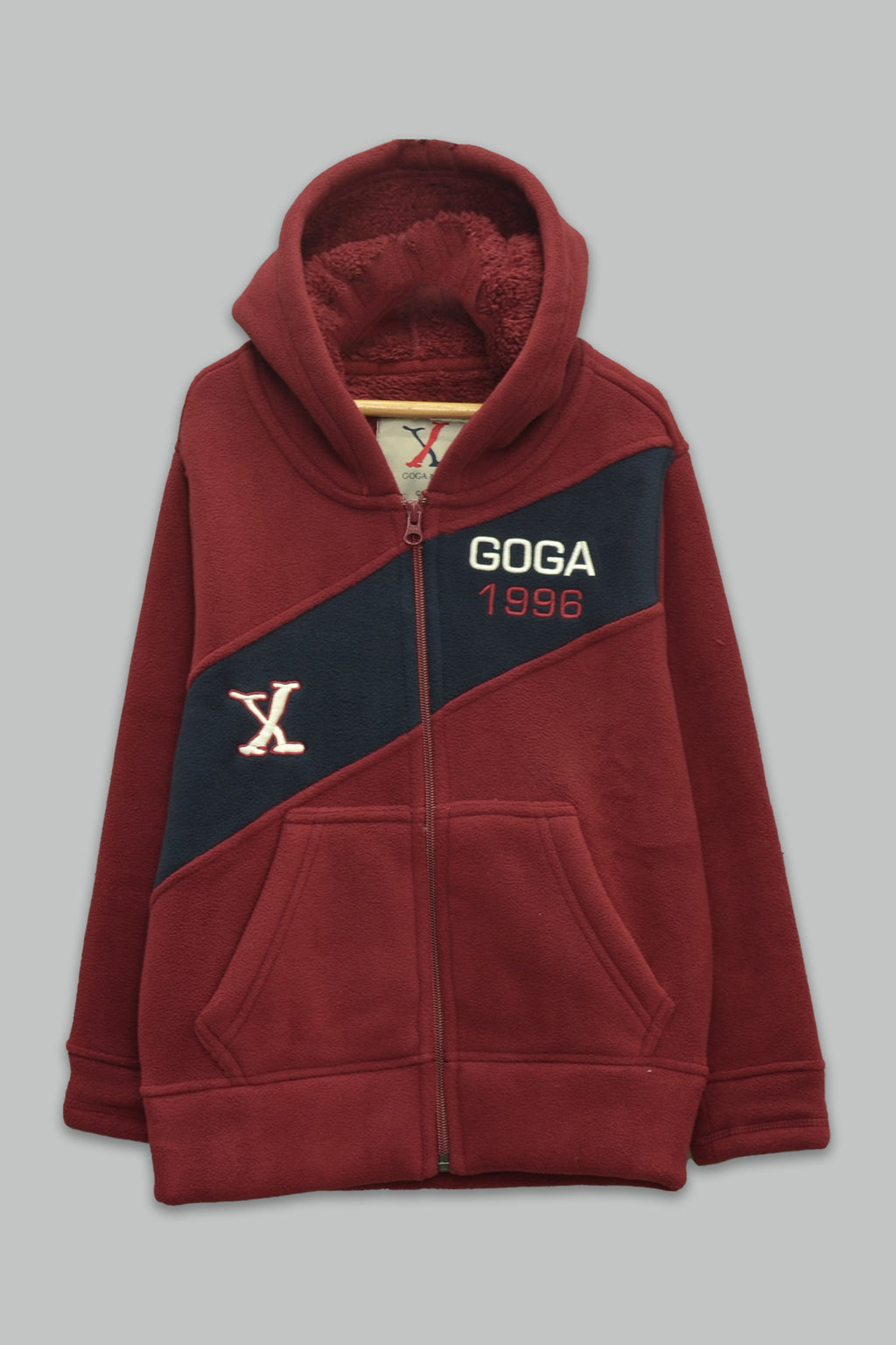 Sudadera sherpa niño bordada con manga larga, capucha ajustable, bolsas frontales y cierre.