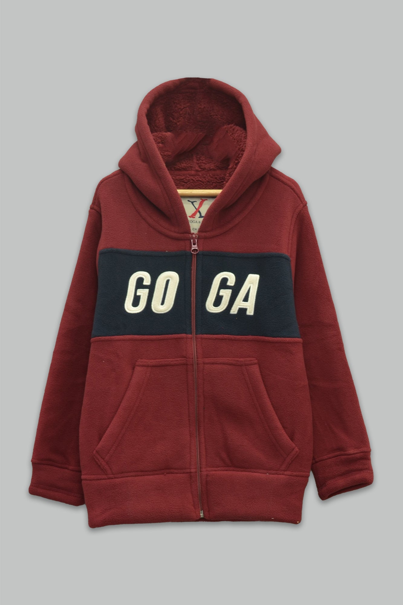 Sudadera sherpa niño bordada con manga larga, capucha ajustable, bolsas frontales y cierre.